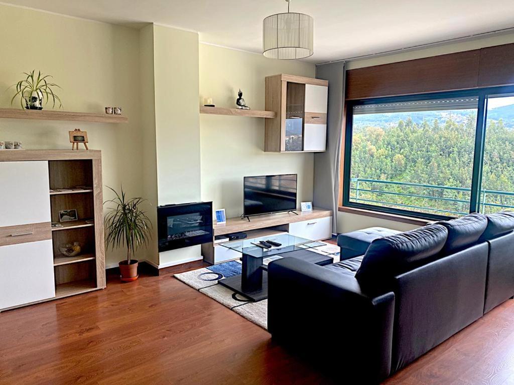 a living room with a couch and a large window at CreaConfort - Casa do Rio in Rio Mau