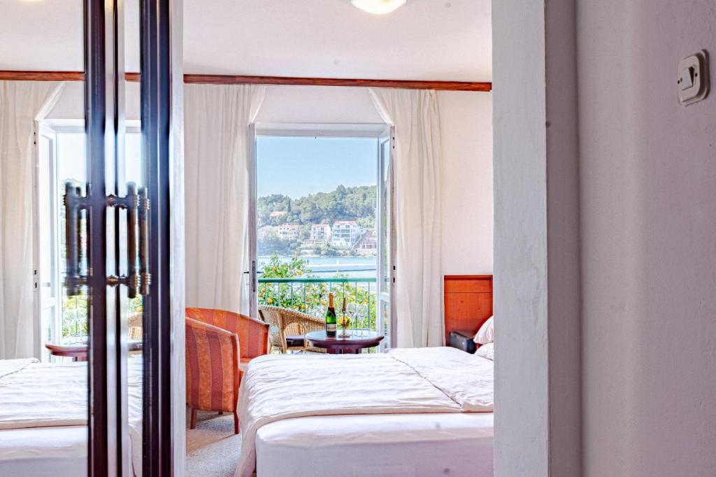 um quarto de hotel com duas camas e uma varanda em Hotel Dalmacija em Vela Luka