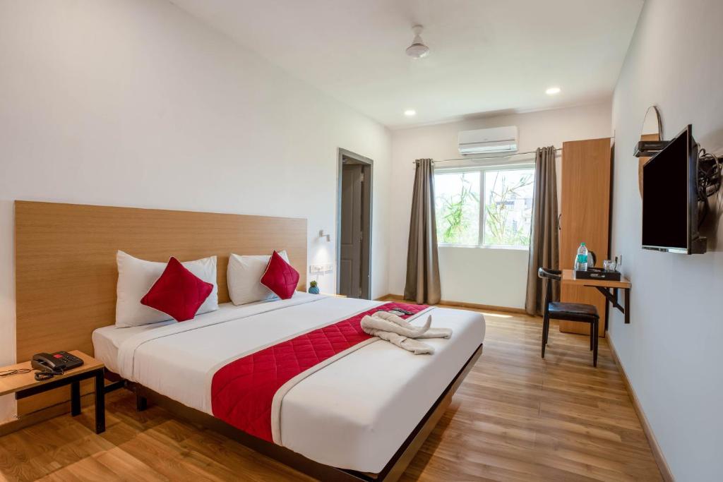 a hotel room with a large bed with red pillows at Alchemy Suites in Bangalore