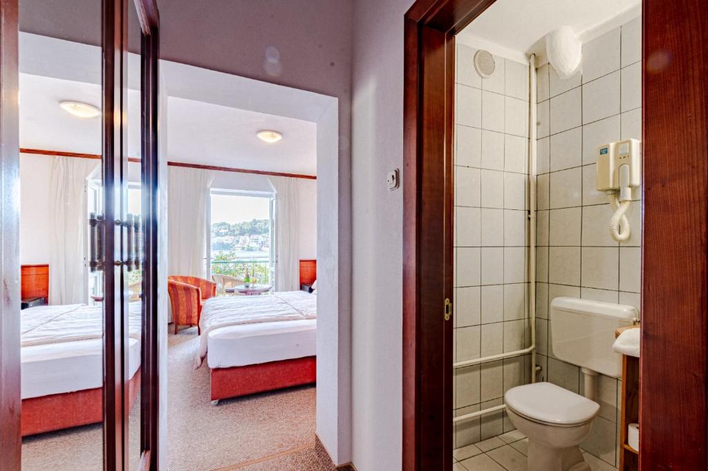 a room with two beds and a bathroom with a toilet at Hotel Dalmacija in Vela Luka