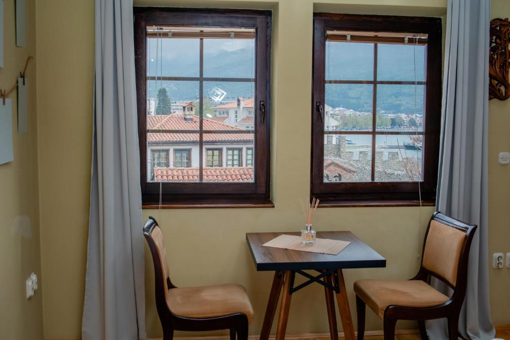 uma mesa e duas cadeiras num quarto com janelas em Family House MARINOV em Ohrid