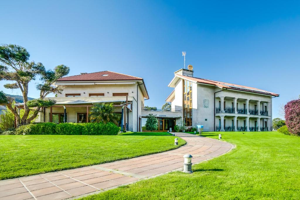 una casa grande con un patio de césped junto a un edificio en Hotel Rural Campaniola en Pontevedra