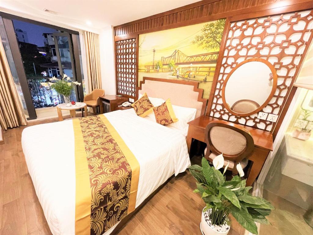 ein Hotelzimmer mit einem Bett und einem Gemälde an der Wand in der Unterkunft DE LA SOIE Hotel & Travel in Hanoi