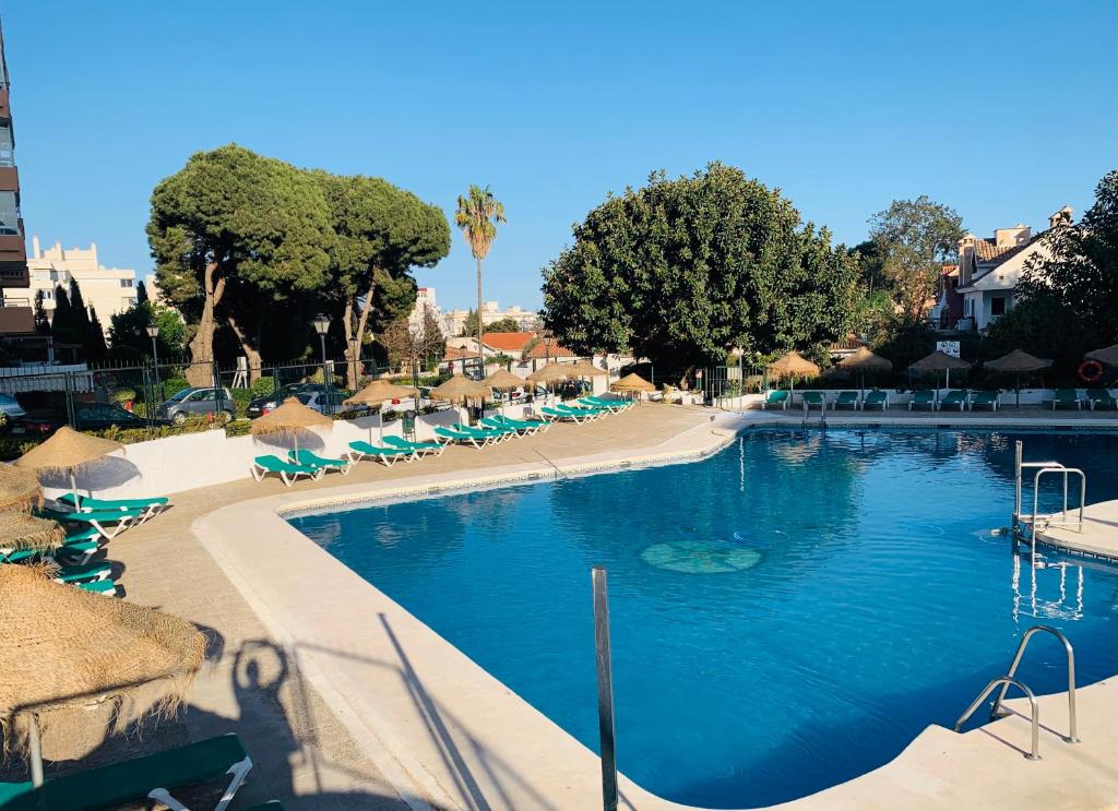 a swimming pool with chairs and umbrellas in a resort at ACUARIO 22 in Benalmádena