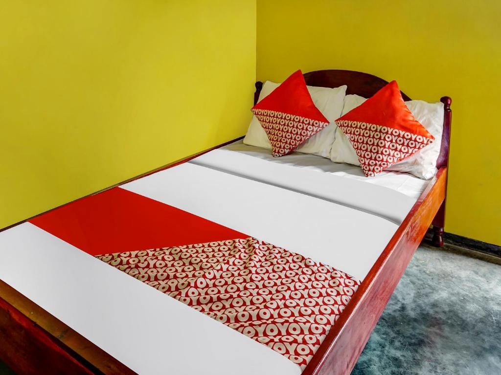 ein Bett mit roten und weißen Kissen darauf in der Unterkunft OYO Homes 90984 Kampung Wisata Ekologi Puspa Jagad in Blitar