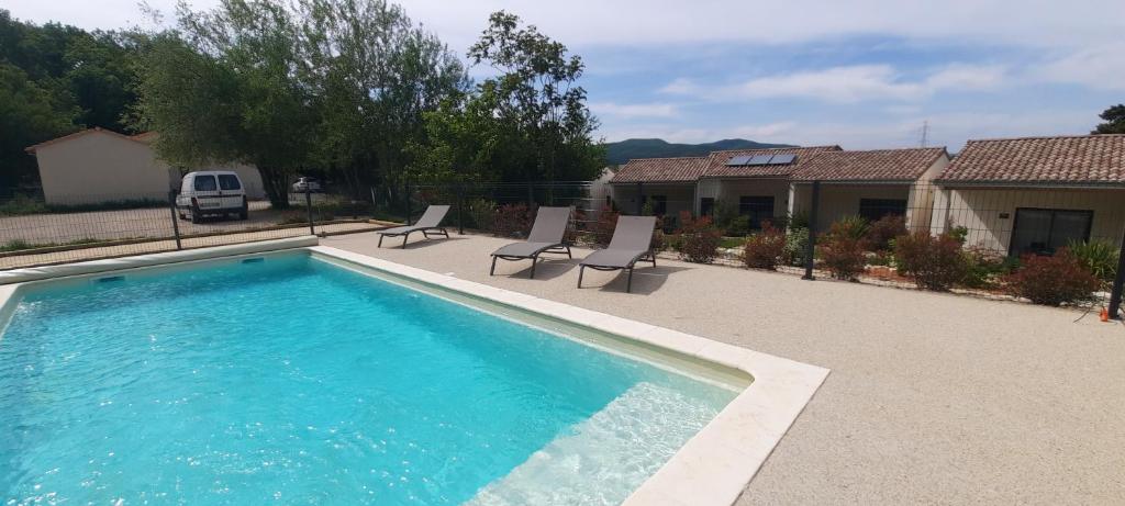 a swimming pool with two chairs and a house at Le Logis de Bérianne in Les Tourrettes