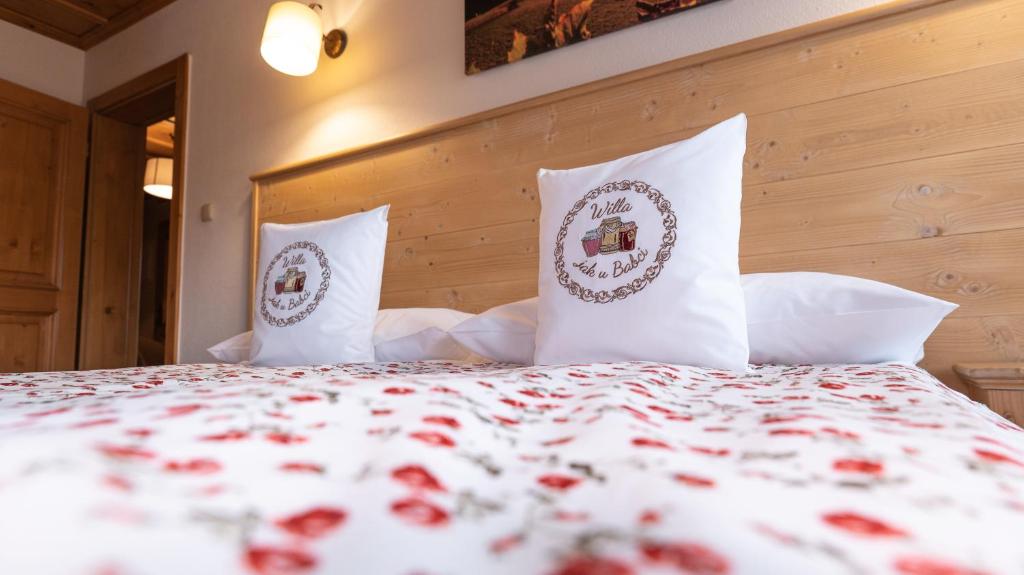 a bed with white pillows and red flowers on it at Willa jak u Babci in Wisła
