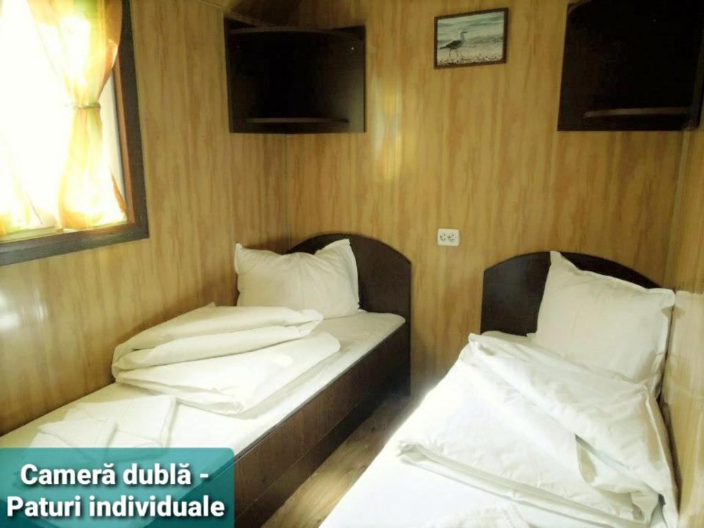 two twin beds in a room with a tv at Hotel Restaurant Plutitor Delta Ways in Nufăru