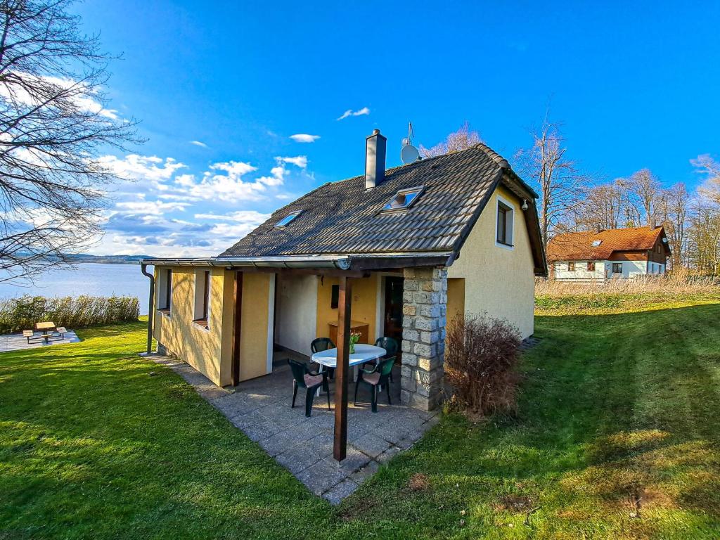 a small house with a table on a patio at Chata Vltavice 251 in Černá v Pošumaví