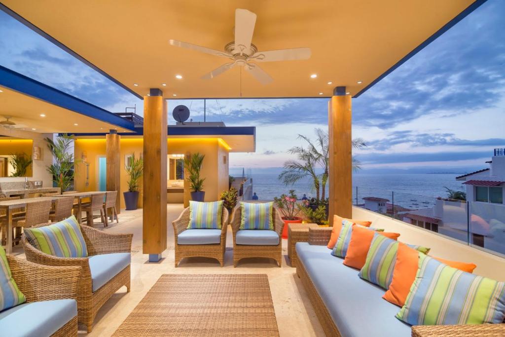 an outdoor patio with chairs and a ceiling fan at LOS MUERTOS BEACH SUITE 101 in Puerto Vallarta