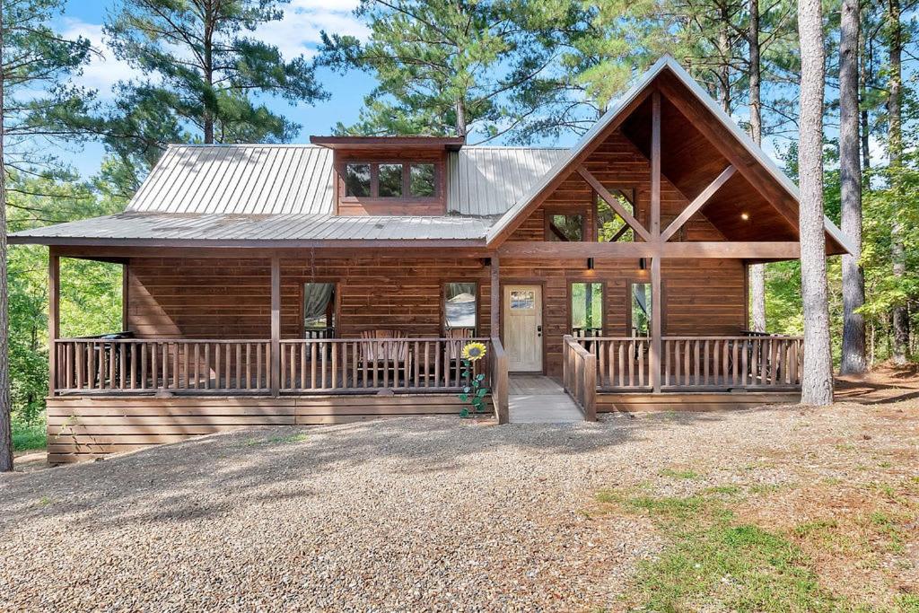 a log home with a large porch and a house at Gorgeous Idyllic Cabin w Hot Tub and Fire Pit Quittin Time is Secluded Romantic Oasis w Luxury Bathroom Double Shower and Bathtub Foosball Table in Broken Bow