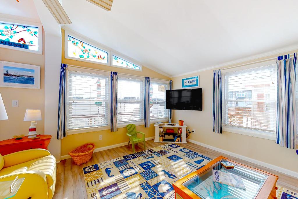 ein Wohnzimmer mit einem Sofa, einem TV und Fenstern in der Unterkunft Montego Bay - 197 Pine Tree Road in Ocean City