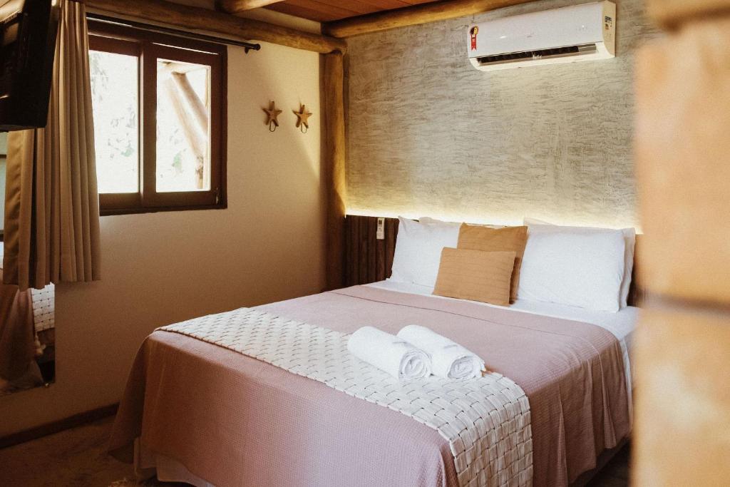 - une chambre avec un lit et 2 serviettes dans l'établissement Vila do Porto, Praia do Patacho - Bangalô Milagres, à Porto de Pedras