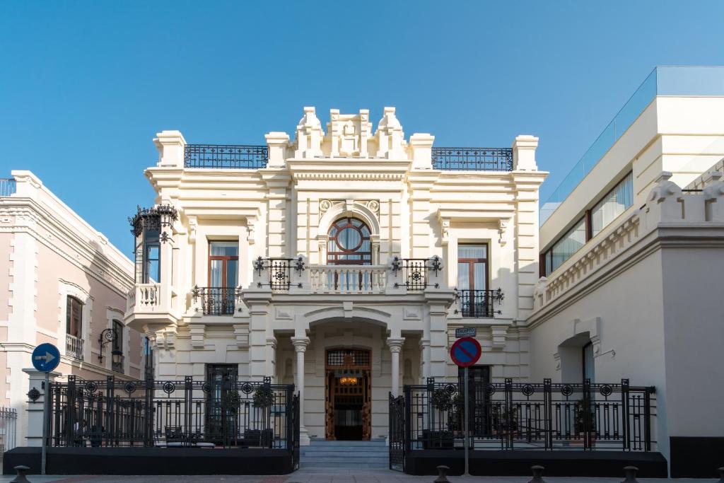 een wit gebouw met een poort ervoor bij CISNES PALACE in Sanlúcar de Barrameda