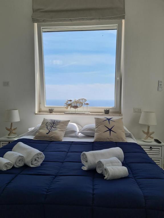 a blue bed with towels on it in front of a window at Casa Leucosia Suites in Capri