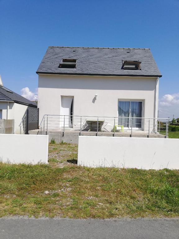 a white house with a fence in front of it at Maison bord de mer in Penmarcʼh
