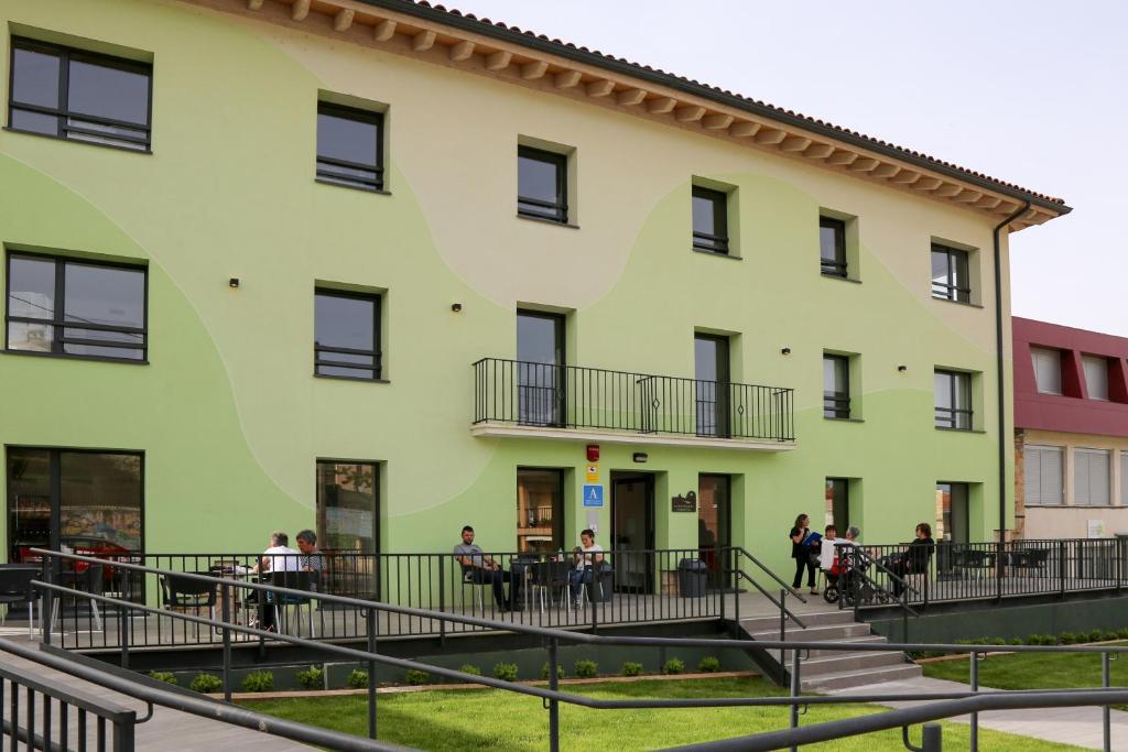 un gran edificio amarillo con gente sentada en mesas al aire libre en ATERPE KANPEZU HOSTEL en Santa Cruz de Campezo