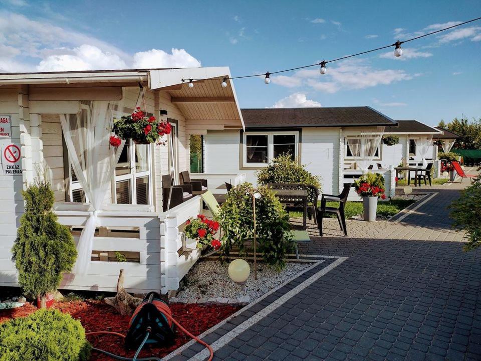 a small white house with a patio with flowers at Domki LA MER in Ustka