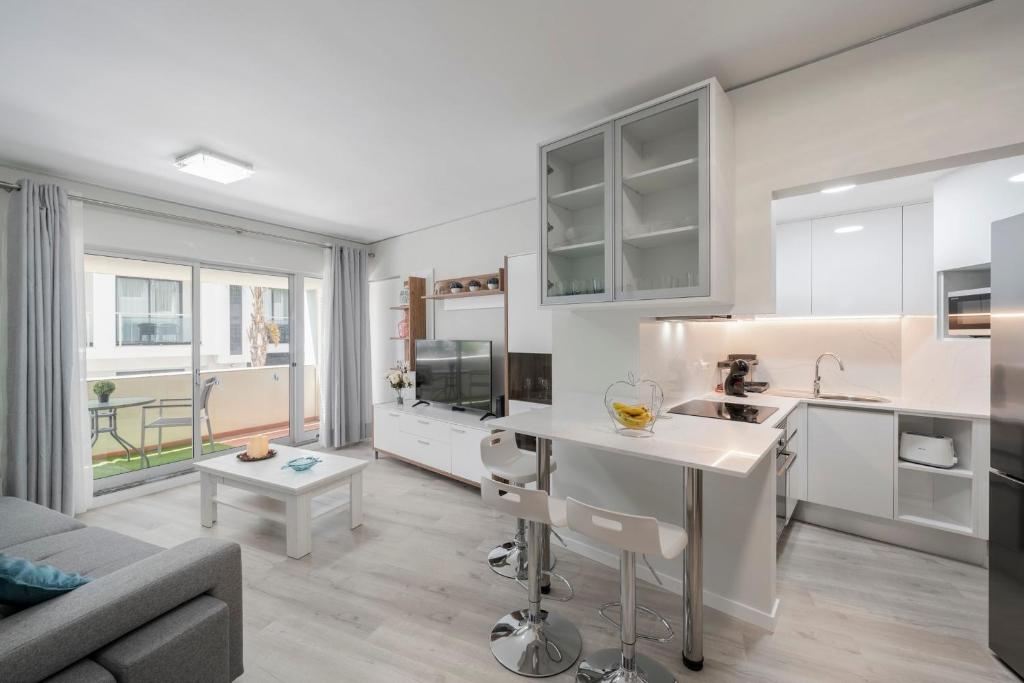 a kitchen with white cabinets and a living room at Varandas do Lido I by An Island Apart in Funchal