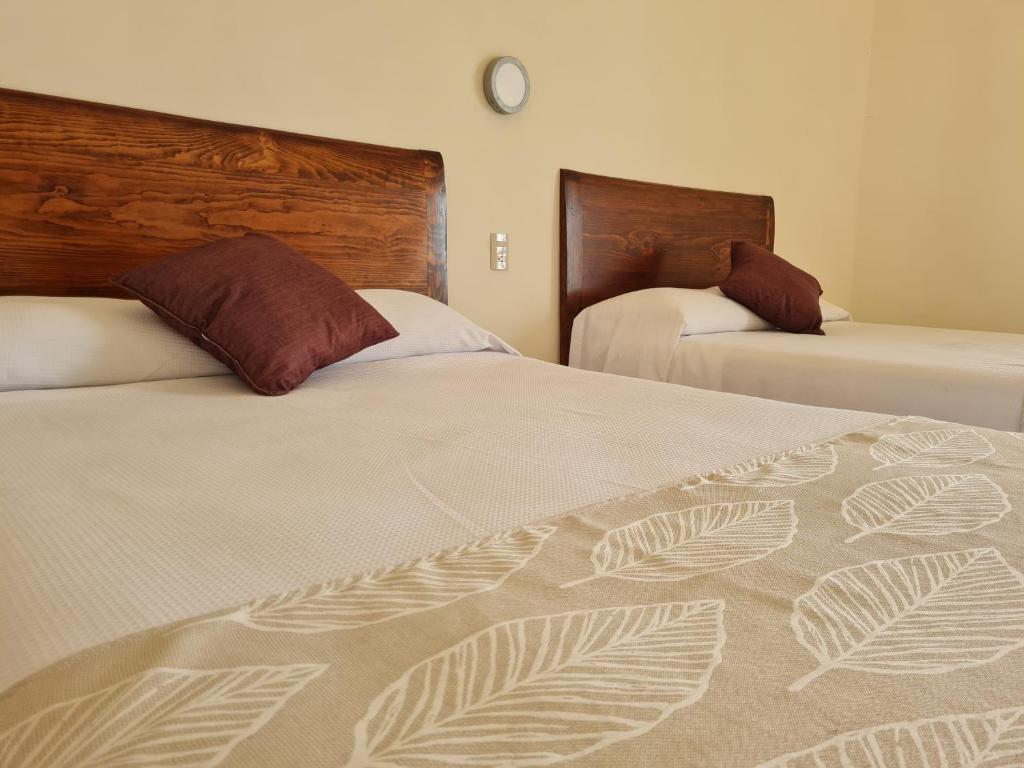 Hotel Catedral في كويرنافاكا: غرفة نوم بسريرين وساعة على الحائط