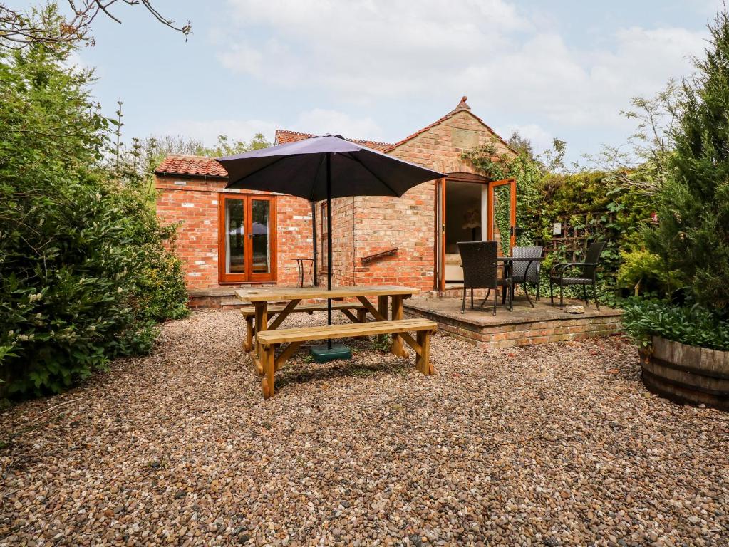 a picnic table with an umbrella in front of a cottage at Wold's View in Grainthorpe