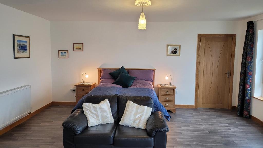 a bedroom with a bed and a leather couch at Vitaver j in Burray Village