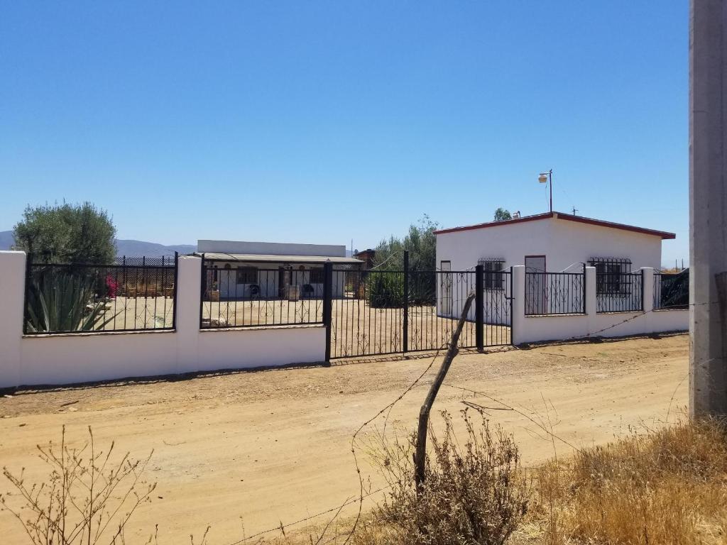 a fence in front of a dirt field with a building at Cabañas Los Laureles Ruta del vino bc in Ensenada