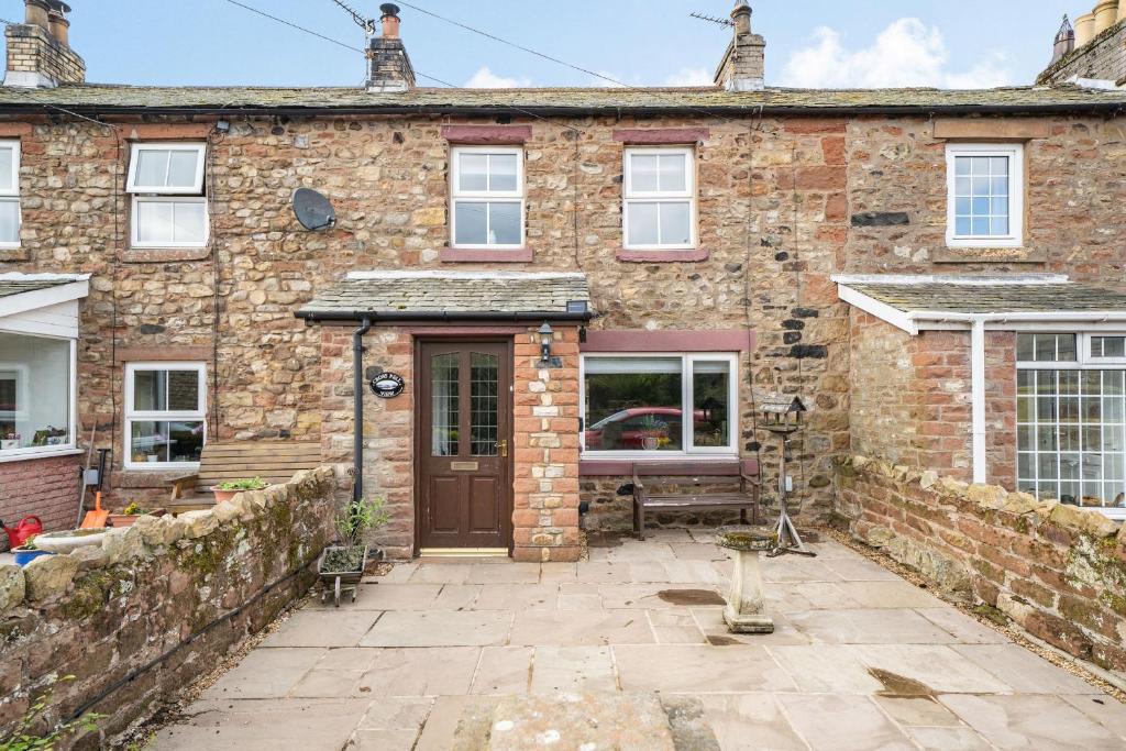 an old brick house with a patio in front of it at Cross Fell View in Dufton