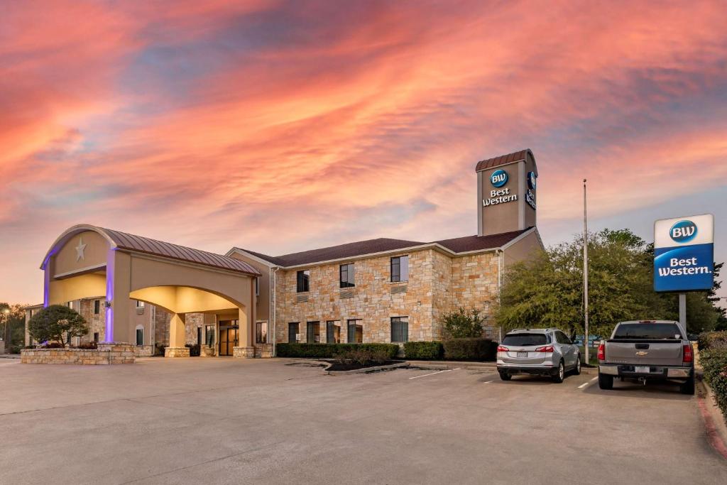 a building with a car parked in a parking lot at Best Western Mineola Inn in Mineola