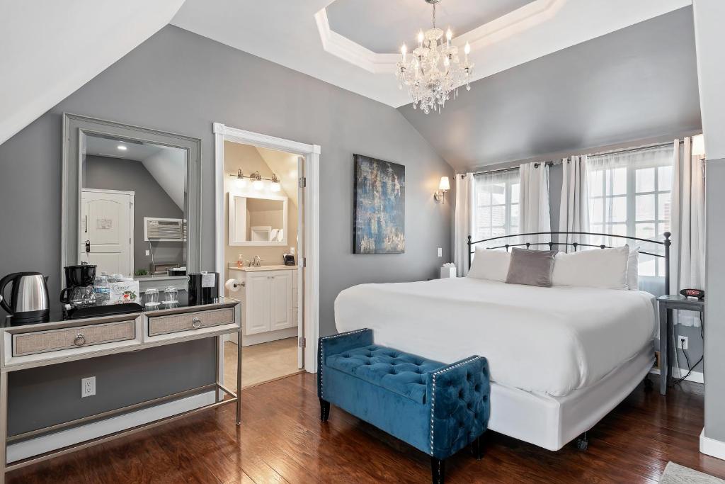 a bedroom with a white bed and a blue chair at New Haven Inn in Solvang