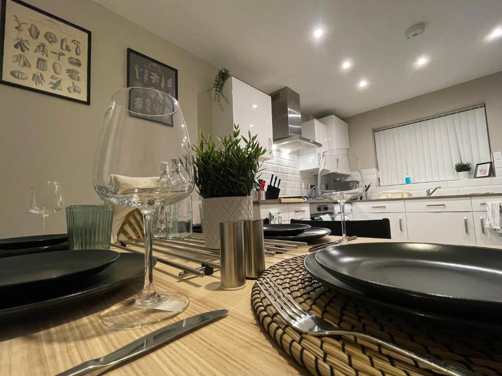 uma cozinha com uma mesa com um prato e copos de vinho em New Stylish Sleeps 7 free parking contractors welcome em Birmingham