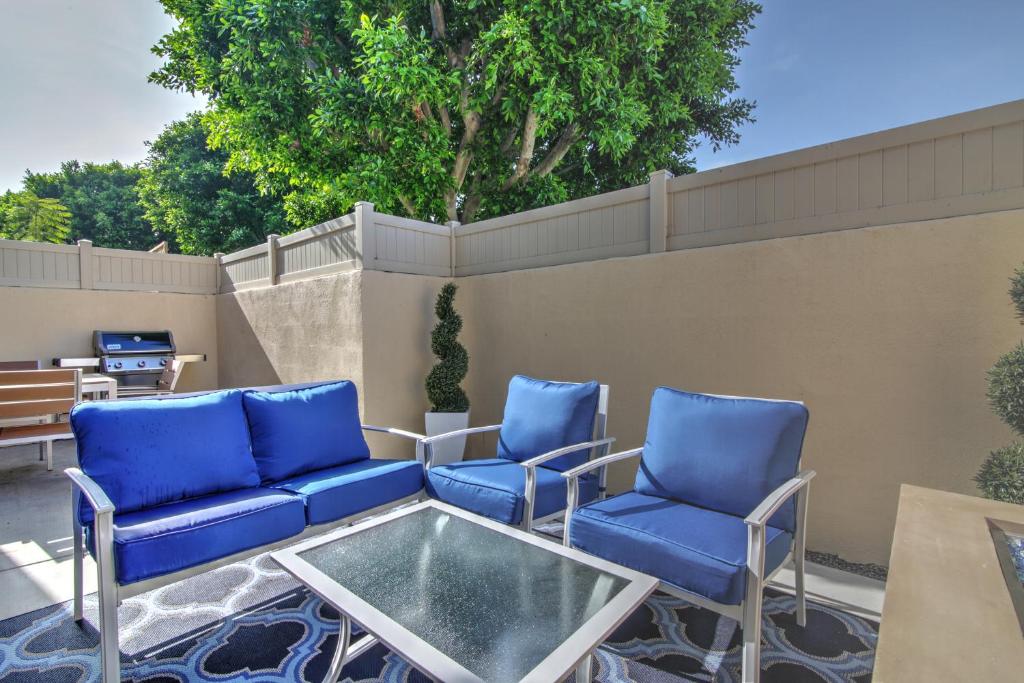 a patio with blue chairs and a glass table at Doorstep to Disneyland Condos in Anaheim