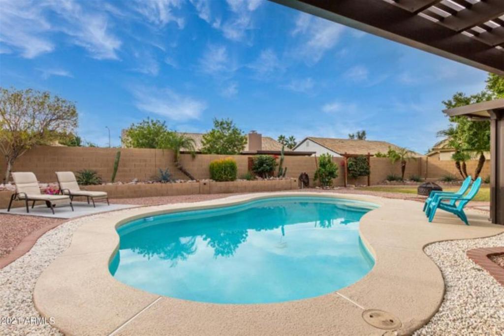 uma piscina com um pátio e cadeiras em redor em Cozy home with pool, fire table, BBQ, RV parking em Mesa