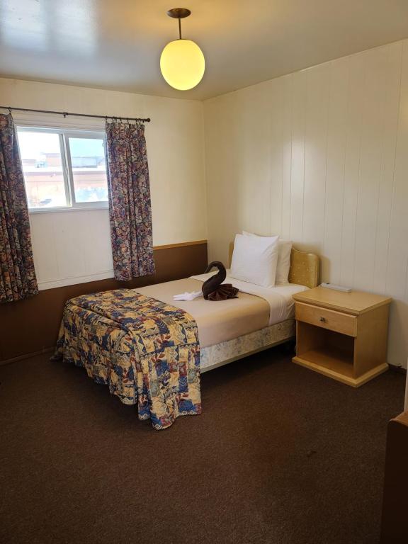 ein Hotelzimmer mit einem Bett und einem Fenster in der Unterkunft Midtown Motel on Alaska Ave in Dawson Creek