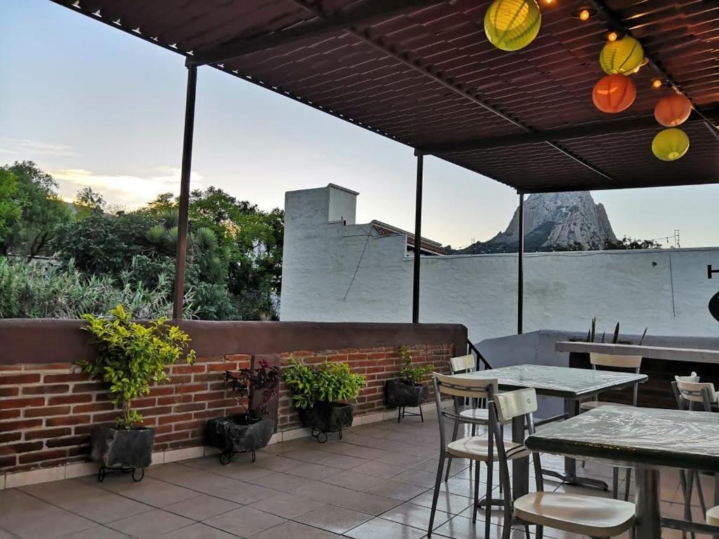 un patio con mesas y sillas con una montaña en el fondo en Hotel Villas Kerendarhú, en Bernal