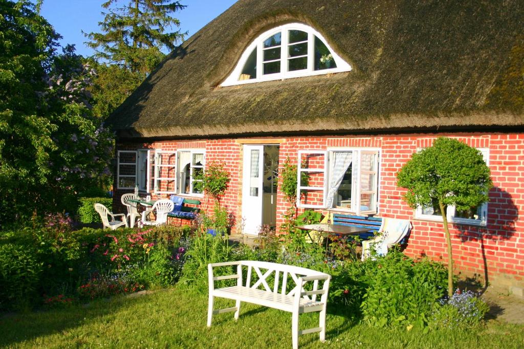 a red brick house with a thatched roof at Im Feriengarten - Ferienwohnung EG in Nardevitz