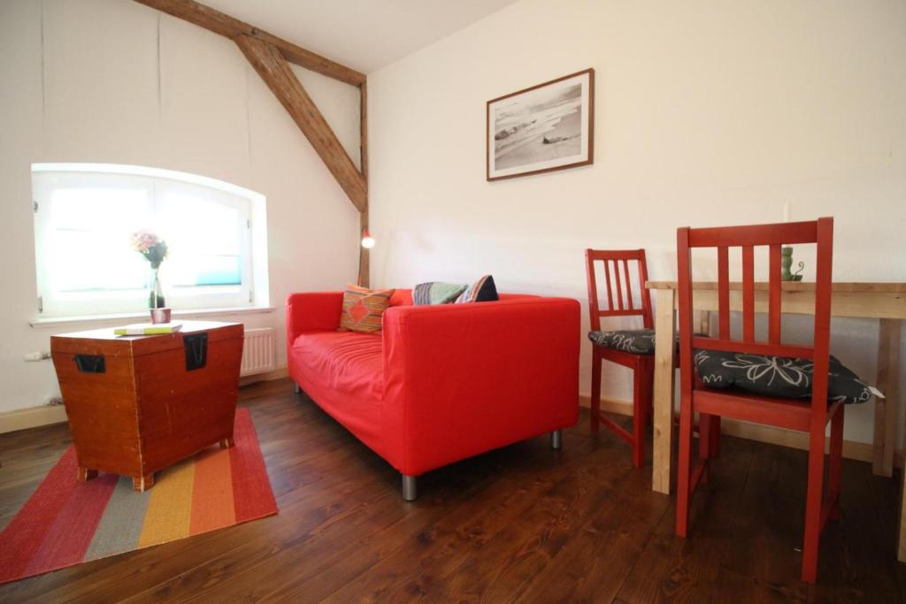 ein Wohnzimmer mit einem roten Stuhl und einem Tisch in der Unterkunft Gutshof Dubnitz Gutshof Dubnitz -Ferienwohnung 4 " Anna " 