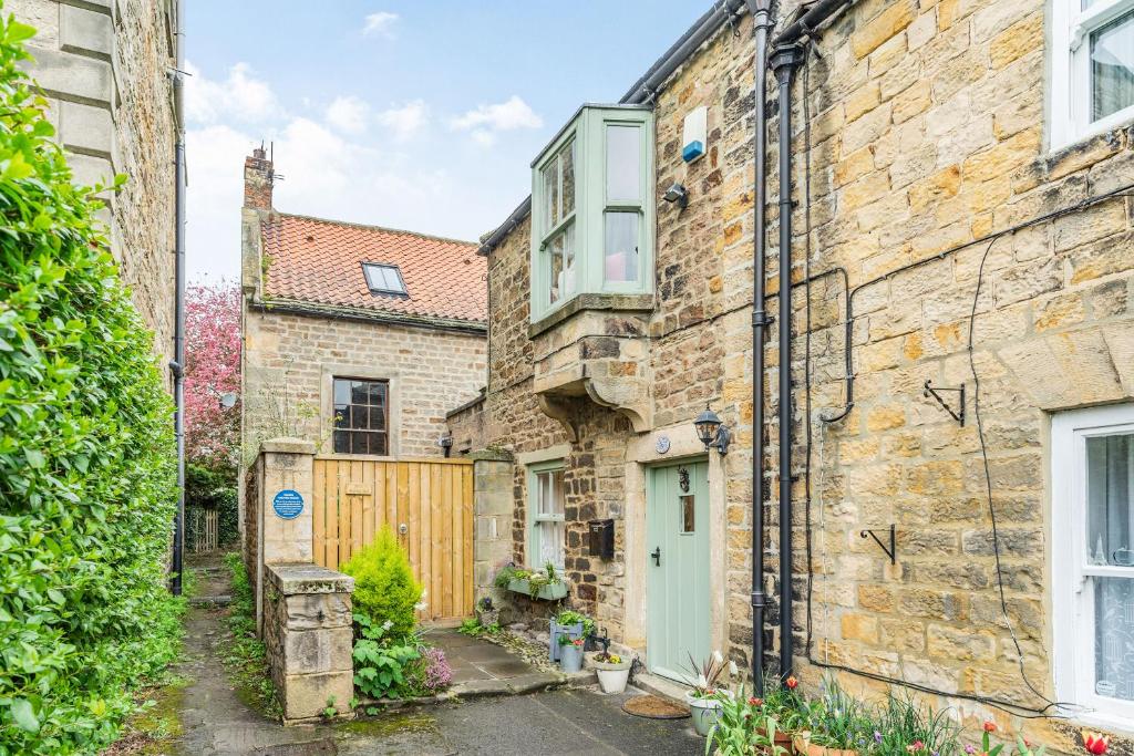 an old stone house with a green door and a gate at Wayside Cottage in Darlington