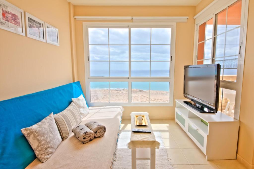 uma sala de estar com um sofá e uma televisão de ecrã plano em Playa Paraiso em Costa Calma