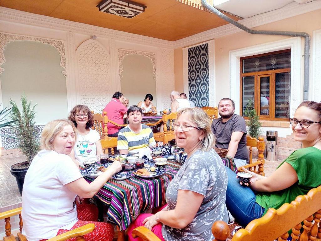 a group of people sitting around a table in a restaurant at Hotel Nasriddin Navruz in Bukhara