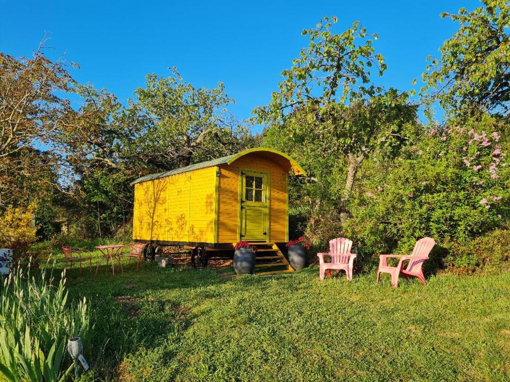 une maison jaune avec deux chaises dans l'herbe dans l'établissement LES ROULOTTES DU PILAT, à Maclas