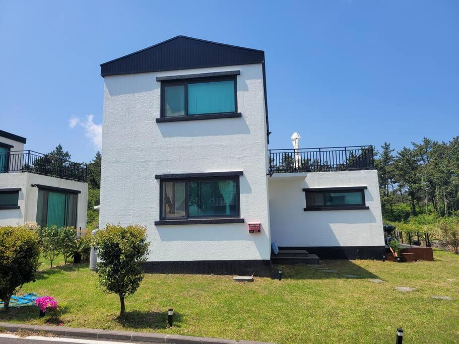 a white house with windows on a green yard at Saeville Stay in Jeju