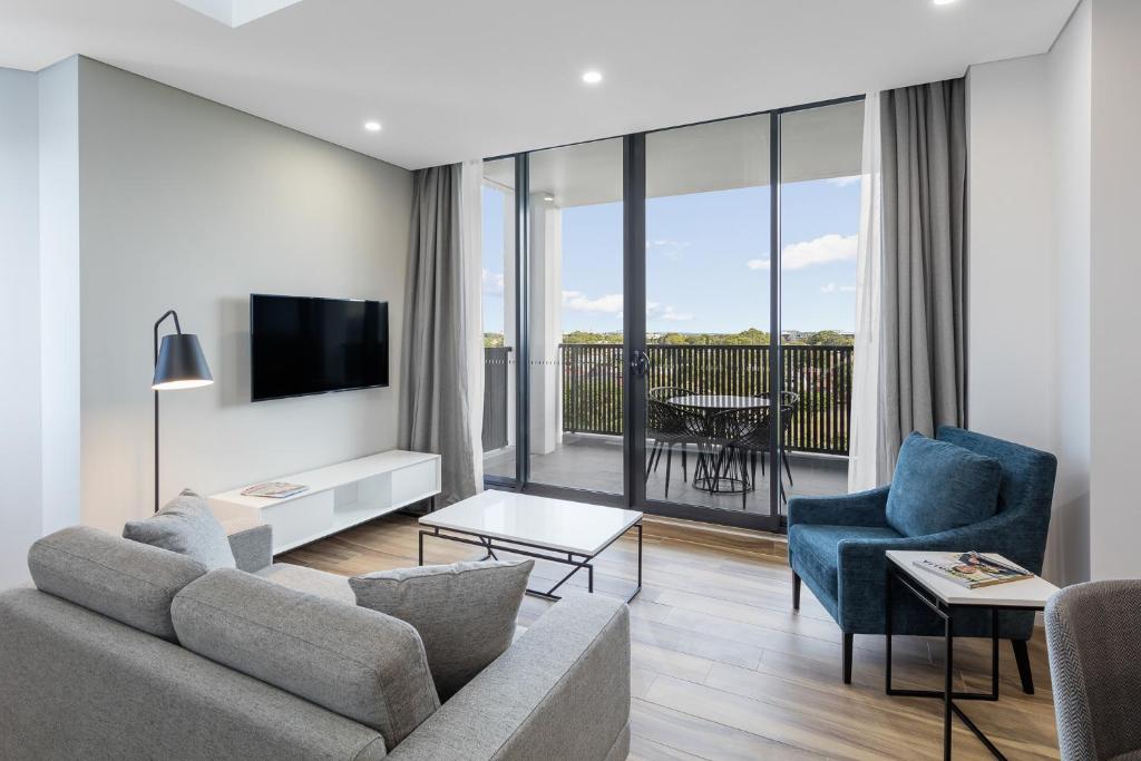 a living room with a couch and chairs and a television at Meriton Suites Coward Street, Mascot in Sydney