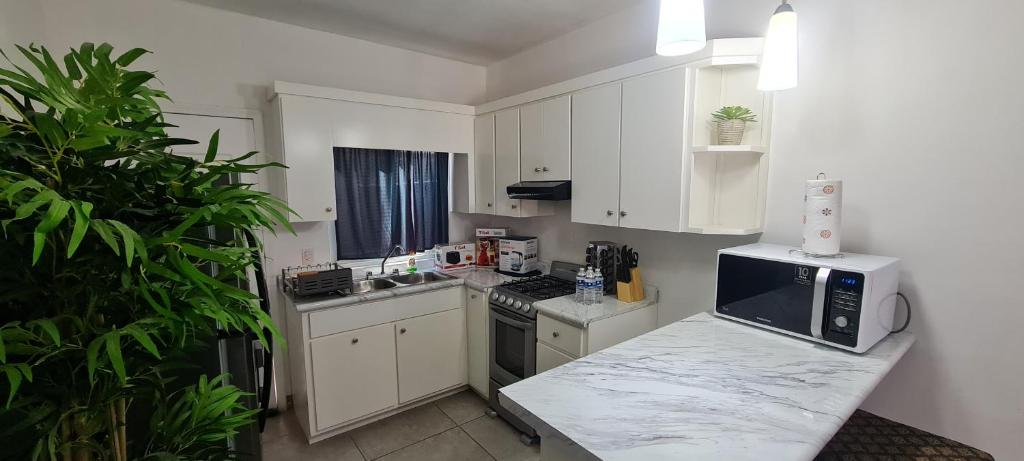 una pequeña cocina con armarios blancos y microondas en GATED AND VERY SECURED WHITE HOUSE 6 MINS FROM THE BEACH, en Puerto Peñasco