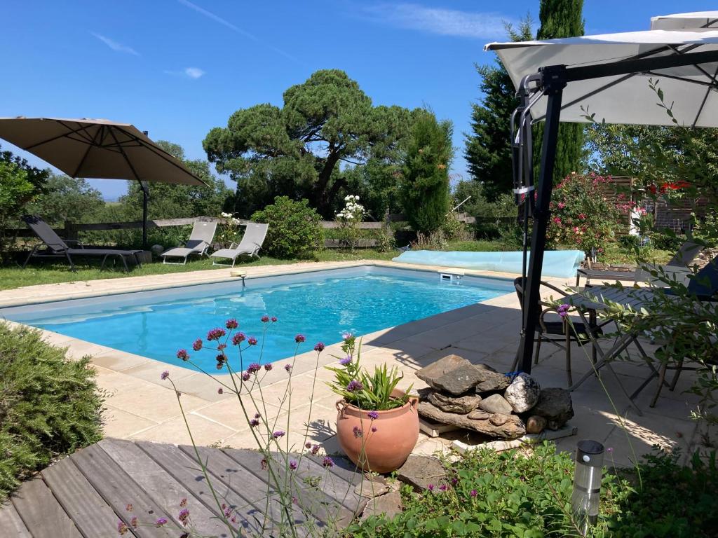 a swimming pool in a yard with an umbrella at Maison d'Hôtes Hameau de Taur in Villefranche-dʼAlbigeois