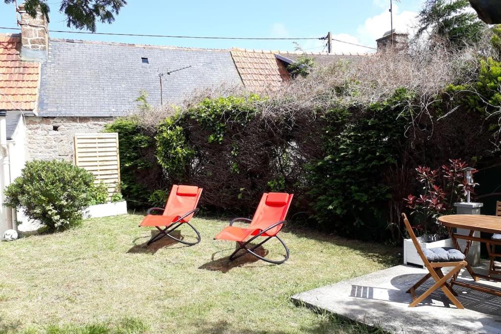 zwei rote Stühle und ein Tisch im Hof in der Unterkunft La p'tite maison de la plage in Fermanville