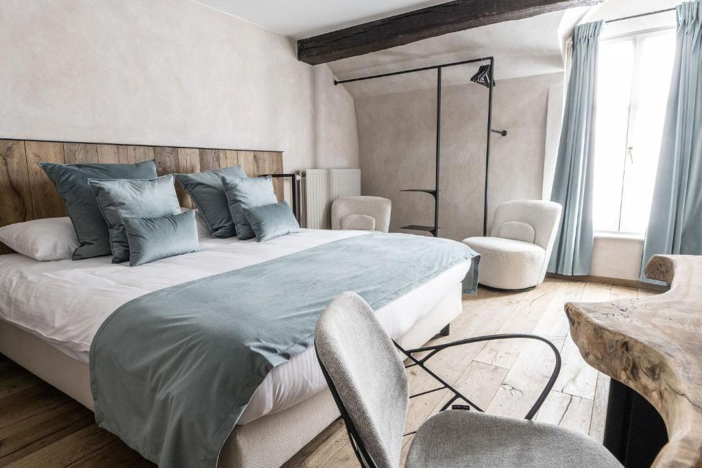 a bedroom with a large bed and chairs in it at Hotel LEA - Maison Caerdinael in Durbuy