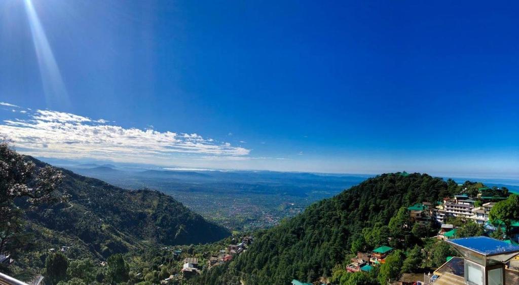 uma vista para uma montanha com árvores e uma cidade em Hotel Norbu House em McLeod Ganj