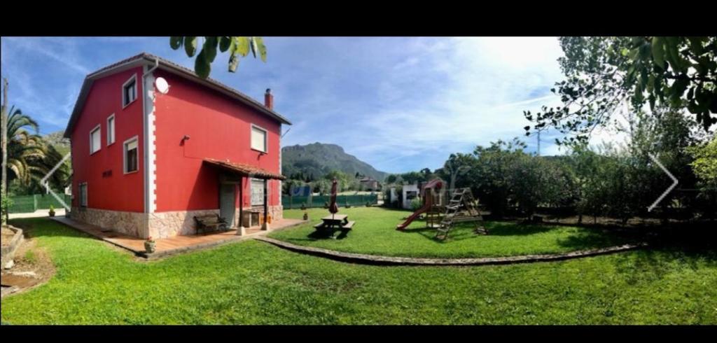 un edificio rojo en medio de un campo verde en Casa La Granda, en Cangas de Onís