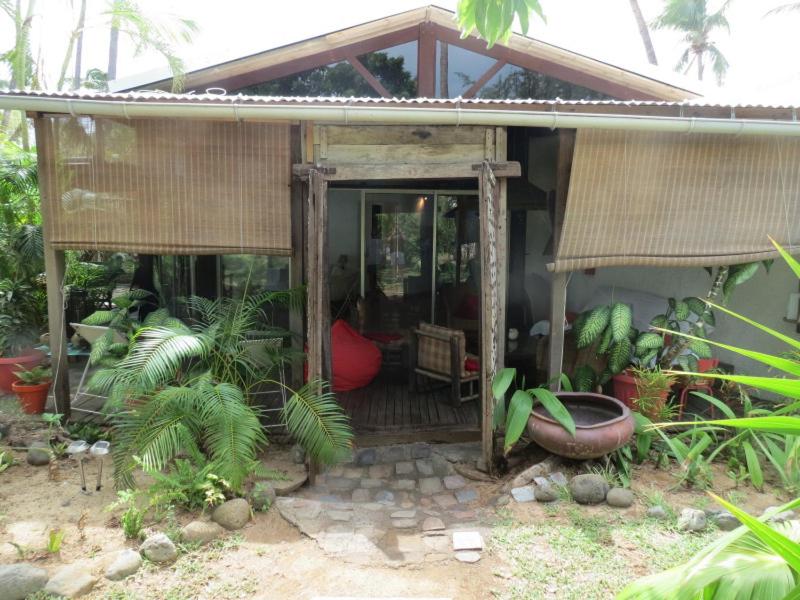 una pequeña casa con un porche con plantas. en Villa de charme proche plage et lagon en La Saline les Bains